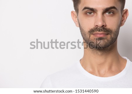 Close up headshot portrait of serious young caucasian man in white t-shirt isolated on grey studio background look at camera, focused millennial guy posing near blank copy space, recommend deal