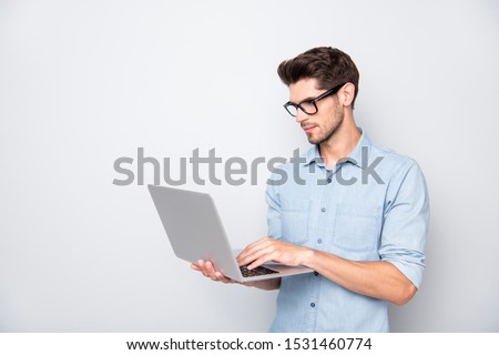 Photo of thoughtful focused clever interested freelancer holding laptop with hands wearing eyeglasses working on deadline project isolated grey color background