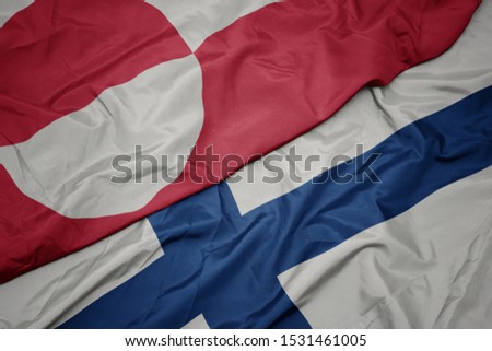 waving colorful flag of finland and national flag of greenland. macro