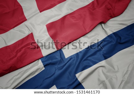 waving colorful flag of finland and national flag of denmark. macro