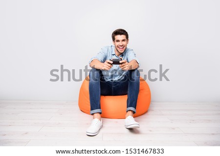 Full length body size photo of trendy man addicted to playing video games wearing white sneakers holding joy stick with hands isolated over grey color background