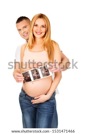 Pregnant couple showing ultrasound pictures of unborn child. Proud parents.