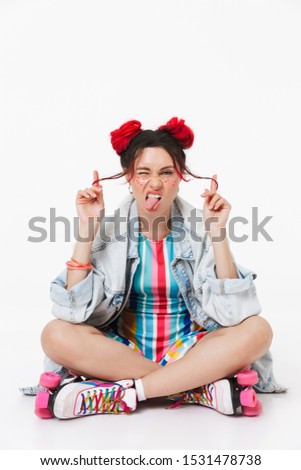 Image of displeased young woman in retro roller skates grimacing while sitting on floor isolated over white background