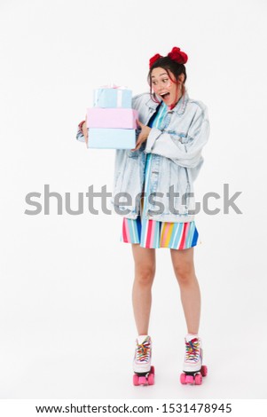 Image of astonished nice woman in retro roller skates holding gift boxes and smiling isolated over white background
