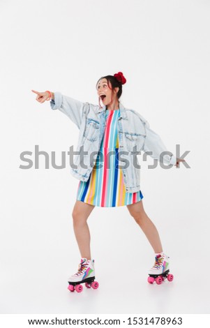 Image of excited nice woman in retro roller skates pointing finger aside at copyspace isolated over white background