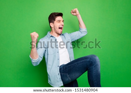 Profile photo of amazing crazy guy yelling loudly celebrating favorite football team victory raise fists and leg wear denim shirt isolated green color background