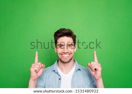 Photo of amazing guy indicating fingers up to empty space advising cool low shopping prices wear casual denim shirt isolated green color background