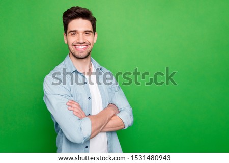 Photo of amazing business guy in excited mood with crossed hands looking forward to start working day wear casual denim shirt isolated over green color background