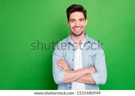 Photo of amazing business guy in excited mood with crossed hands looking forward to start working day wear casual denim shirt isolated over green color background