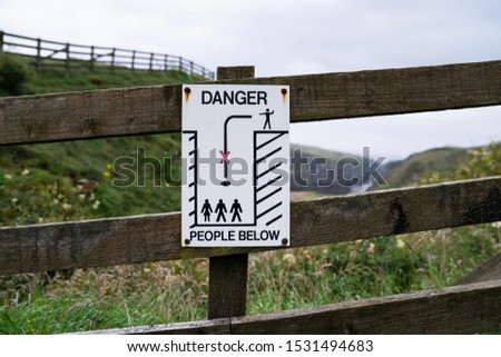 "Danger. People below" sign in a fence