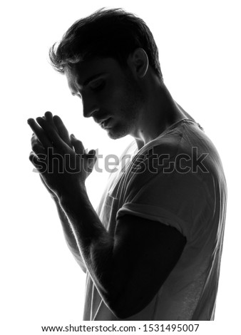 Silhouette of young strong man portrait in mystery shadow light on white isolate background. Anonymous concept.