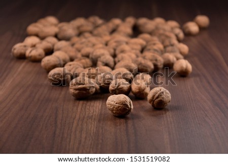 Walnuts on a wooden background stock images. Pile of walnuts with nutshell. Walnuts close up on wooden background. Walnuts on the table