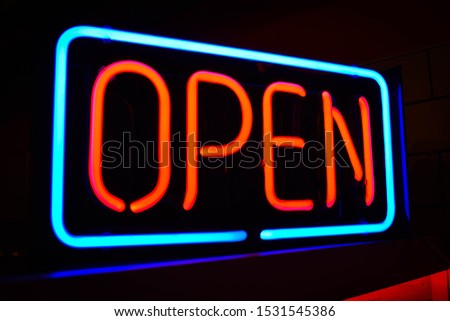 A blue and red neon sign that says "open". 