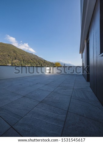 Large terrace with large marble tiles overlooking the Swiss hills in Ticino. Nobody inside. Sunny day, blue sky