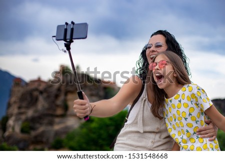 A mother is posing for selfie with selfie stick at outdoors at vacation, Selfie concept with family and happiness