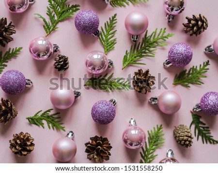 Pink background and pink different Christmas ball, cones and Christmas tree branch flat lay

