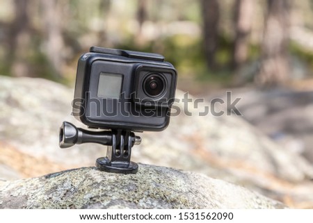 Image of an action camera outdoors on a rock in a forest.