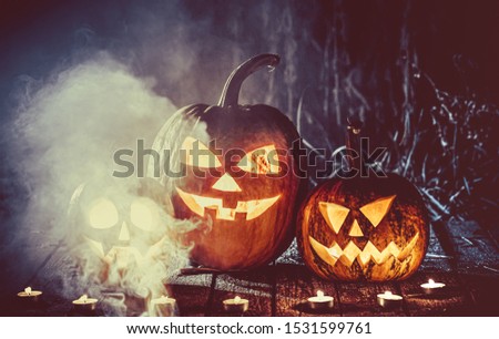 Halloween pumpkins head jack lantern with candles around on the old boards in a spooky night landscape. Soft focus. shallow DOF