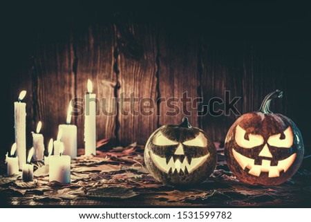Halloween pumpkin with glowing face on a wooden background with candles