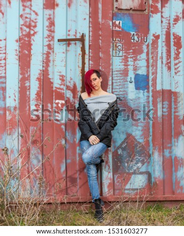 Portrait of a beautiful red-haired girl leaning against a rusty wall