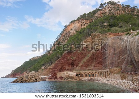 Mallorca landscape. Estellencs beach with small dock or boat port. Colorful tall mountain with safety nets. Camp de Mar, Es Port, Balears Islands, Spain. A great design for card, print or picture.