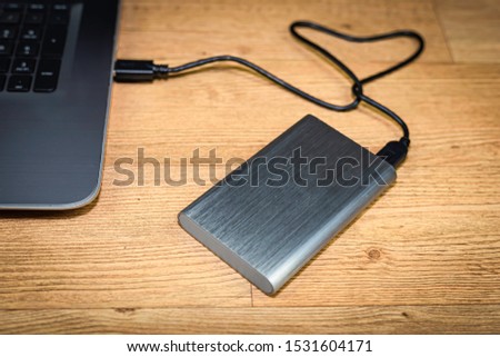 External hard drive connect to laptop on wooded wallpaper background