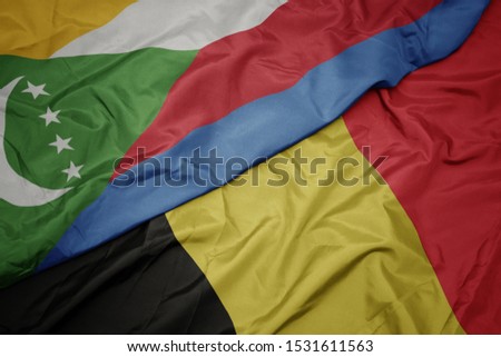 waving colorful flag of belgium and national flag of comoros. macro