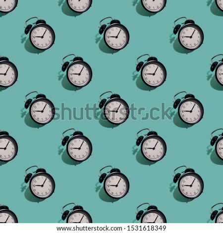 Many black classic style alarm clock with hard shadow isolated on green background. Smile time concept. Seamless pattern