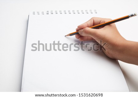 hand holding pen writing on blank white paper. Hand write in the white blank sheet.
