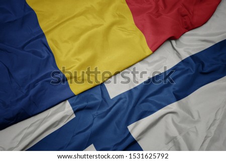 waving colorful flag of finland and national flag of romania. macro