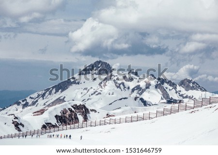 Beautiful snow-covered majestic mountain in a ski resort against a white lush cloud. The concept of rest in the ski resort and beautiful nature