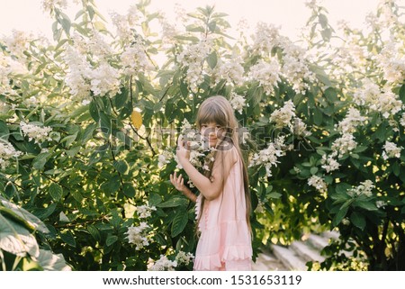 little girl with long hair hugging flowers happy in botanical garden outdoors 