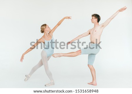 Two athletic modern ballet dancers are posing against white studio background