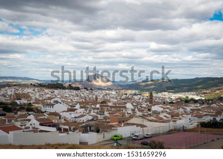 The view down over the terracotta roofs of the medieval city of Antequera in Andalusia, Southern Spain. The legendary “Peña de los Enamorados” (The Rock of the Lovers) sunlit in the background.