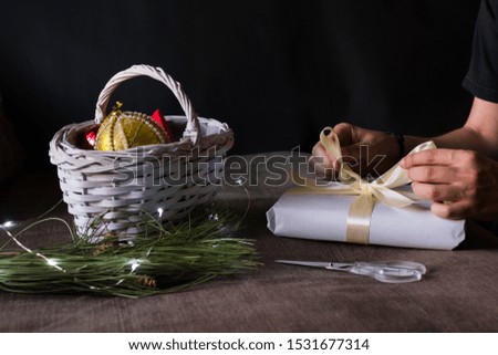 Stock photography of christmas accessories on black background, hands of a man appear. Still live, gifts