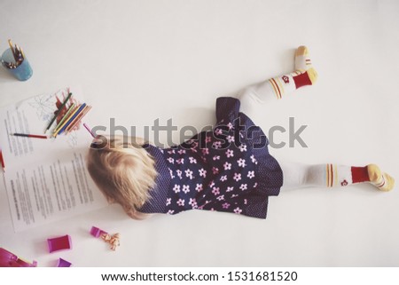 little girl lying draws on the floor