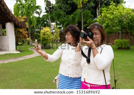 Two female friends are taking pictures according to their own style.