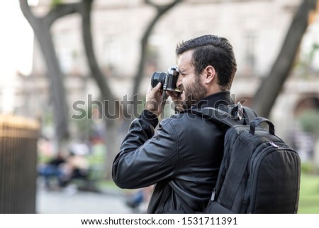 Portrait of handsome bearded photographer and camera taking photos outdoor.