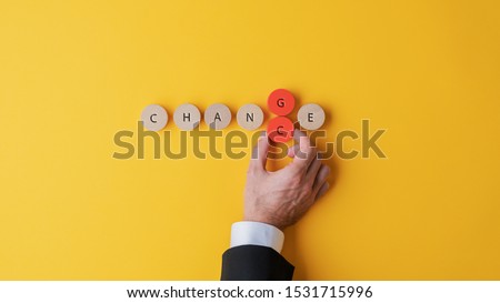 Hand of a businessman changing the letters G and C to transform a Change sign into Chance spelled on wooden cut circles. 