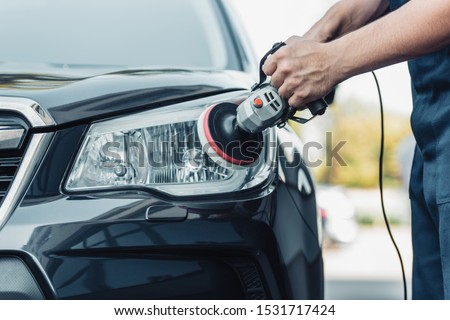 cropped view of car cleaner polishing headlamp with polish machine Royalty-Free Stock Photo #1531717424