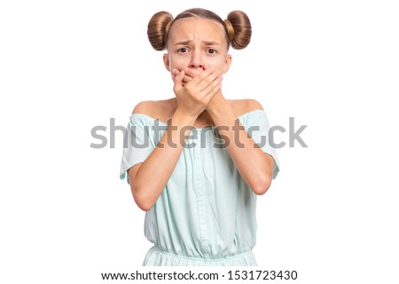 Portrait of amazed teen boy covers her mouth with hands. Child with very large eyes in surprise looking at camera. Caucasian young teenager, isolated on white background. Speak no evil concept.