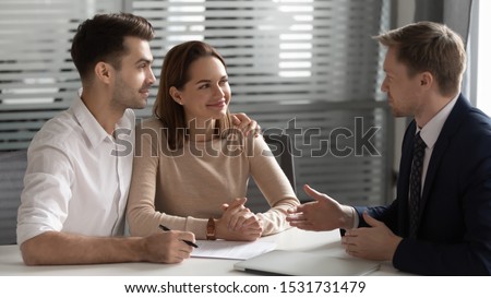 Confident manager, realtor, estate agent consulting young couple about contract terms at meeting in office, happy man and woman taking loan, mortgage or insurance, negotiations concept Royalty-Free Stock Photo #1531731479
