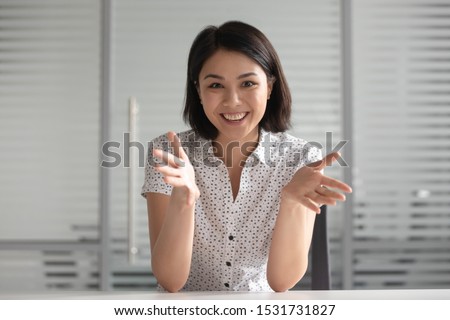 Smiling young Asian businesswoman looking at camera and talking, making video call, mentor coach tutor recording webinar, online course, teaching language, hr manager holding distance job interview Royalty-Free Stock Photo #1531731827