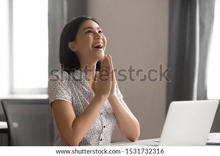 Happy excited Asian businesswoman puts hands in prayer, thanking fate for business success, smiling employee celebrating great work results, student received good news, positive exam result Royalty-Free Stock Photo #1531732316