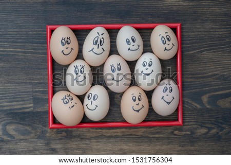 Picture red frame and many funny eggs smiling on dark wooden wall background, close up. Eggs family emotion face portrait. Concept funny food