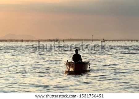 fisherman silhouette at Sunset in Venice lagoon chioggia harbor from a boat landscape
