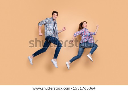Full length body size side profile photo of gorgeous beautiful nice charming couple with him running after her and her trying to escape him in jeans denim checkered beige pastel color background