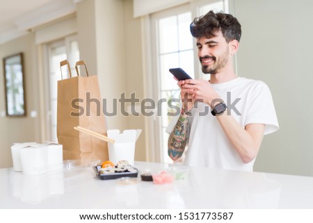 Young man taking pictures with smartphone of sushi asian food from take away delivery