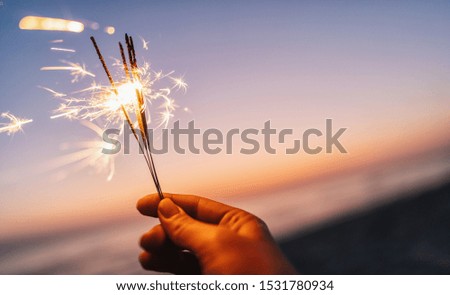 hand holding sparkler at sunset light
