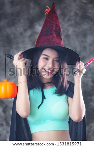 Happy beautiful woman in witch halloween costume with hat. Surprised woman holds pumpkin. Halloween concept